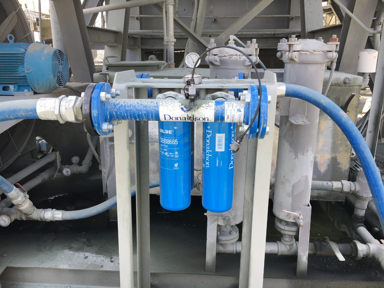 Lösung von Donaldson im Vordergrund mit angebrachtem Mini Mess Sample Port zum ordnungsgemäßen Ablesen von ISO-Codes. Die Originalfilter an der Rückseite werden getrennt, und die Flüssigkeit fließt durch die Donaldson-Filter.