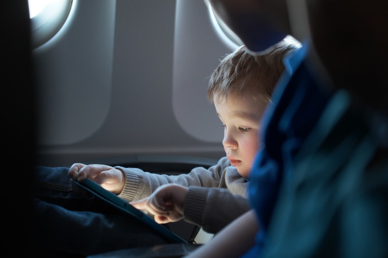Uma criança usa um tablet em seu assento de avião 